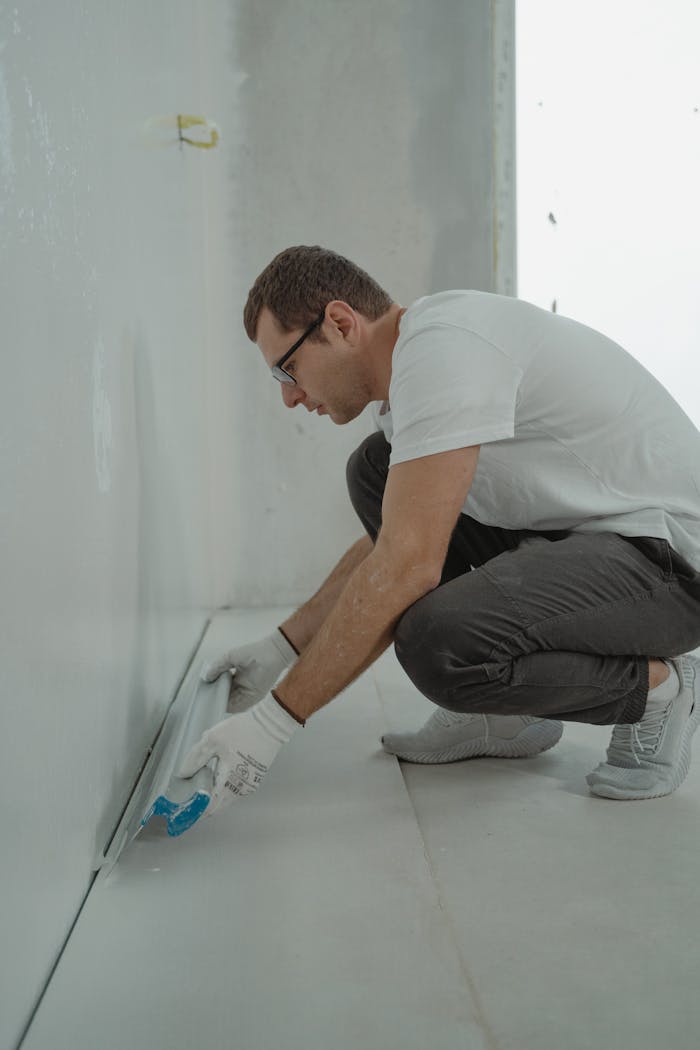 creative-01 A man wearing casual attire working on a home renovation project indoors with painting tools.