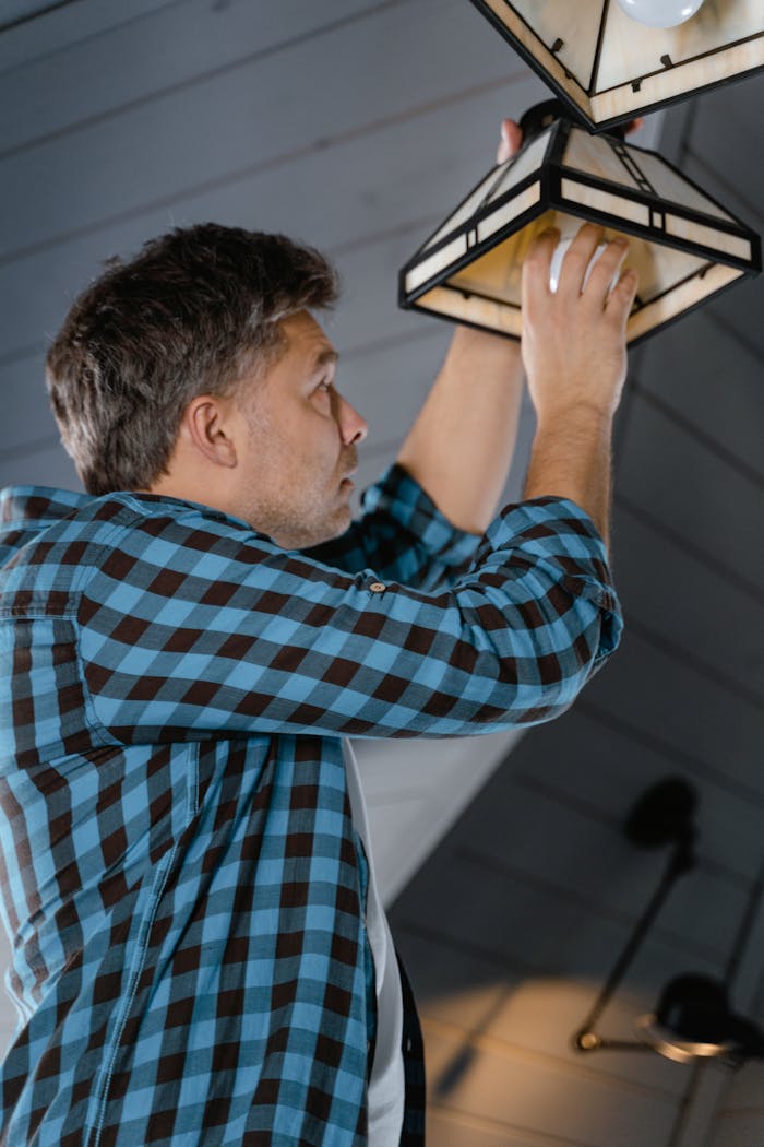 mobile-02 Man in a plaid shirt installs a lightbulb in a stylish interior setting.