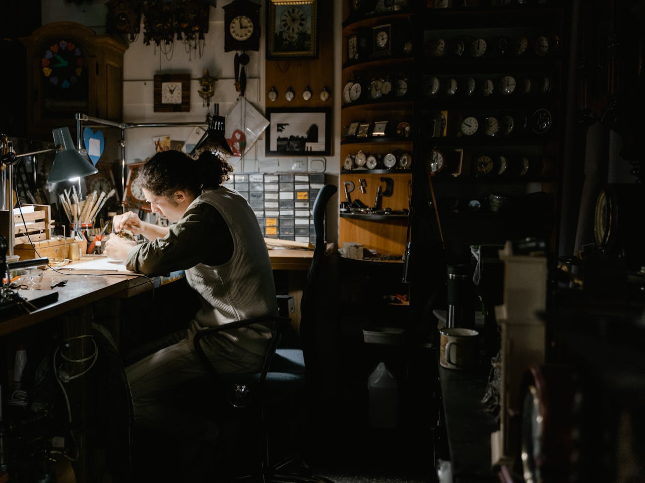 creative-03 A watchmaker meticulously repairing watches in a dimly lit workshop filled with clocks and tools.
