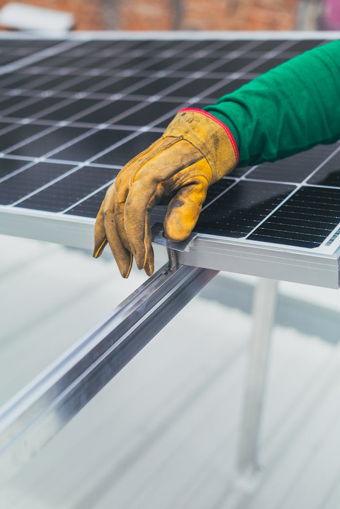 mobile-01 Close-up of a worker's hand in protective glove installing a solar panel.